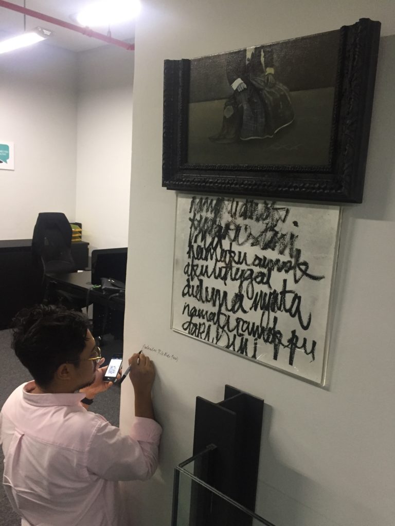 Signing on the wall below his art piece